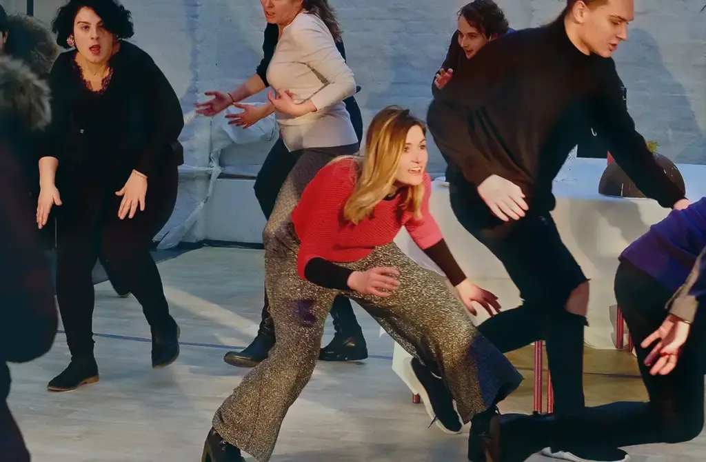 Gruppe im Abendkurs bewegt sich gemeinsam durch den hellen Übungsraum, vorne eine Teilnehmerin im roten Pullover.