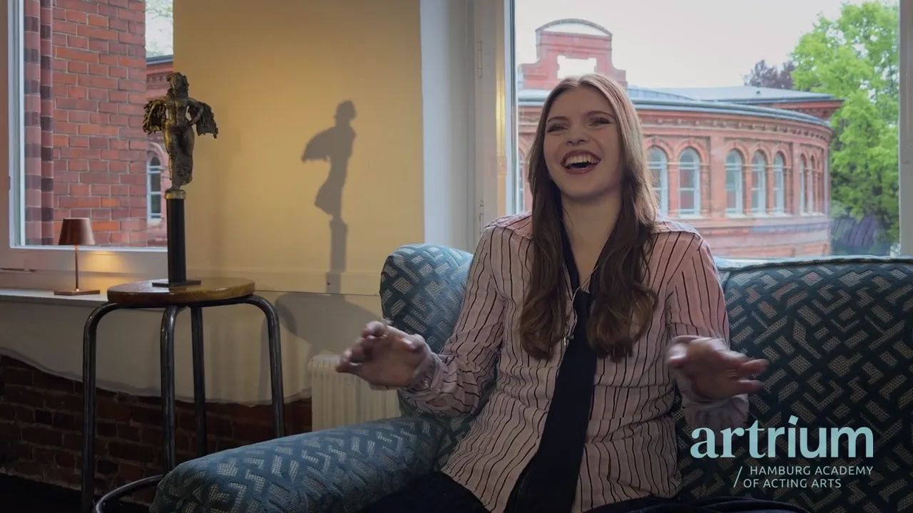 Lilly sitzt lachend auf einem Sessel am Fenster und erzählt von ihrem Gasttag.