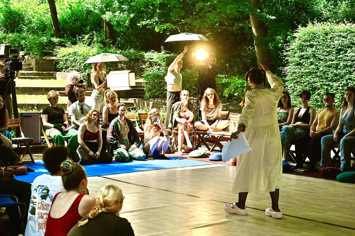 Schauspielszene der Sommerakademie auf der Outdoorbühne im Grünen, mit Kamera und Scheinwerfer