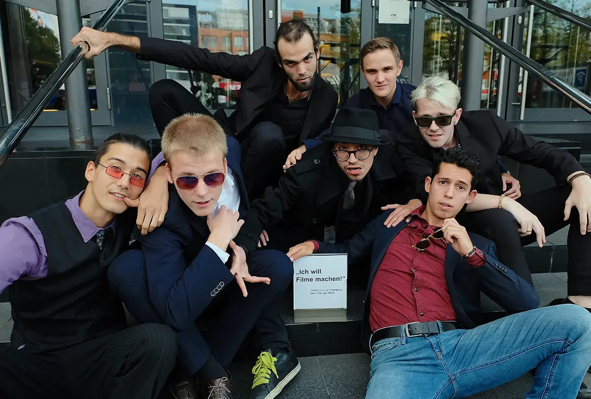 Gruppe junger Schauspielschüler des Artrium sitzt gemeinsam auf einer Treppe vor einem Hamburger Gebäude