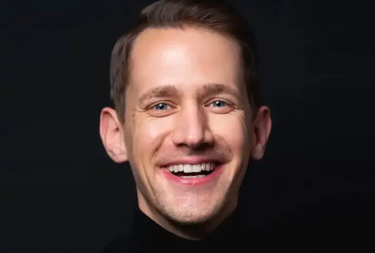 Porträt des lächelnden Dozenten Johannes P. P. Braun im schwarzen Rollkragenpullover vor dunklem Hintergrund.