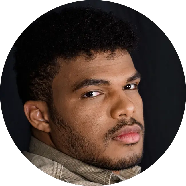 Porträt von Moises Silva vor dunklem Hintergrund, den Blick seitlich in die Kamera gerichtet.