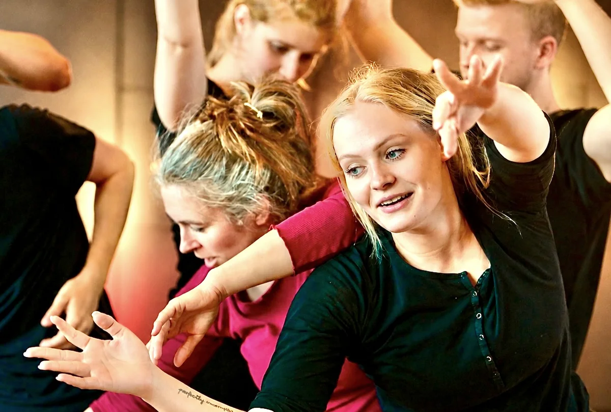 Mehrere Teilnehmende stehen dicht beieinander und strecken die Hände aus, eine Übung aus dem Ensembletraining.