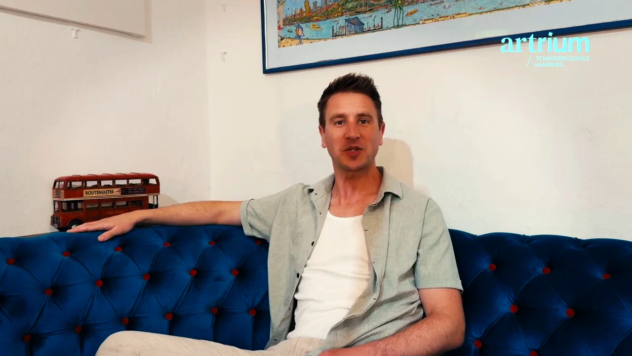 Frederik sitzt auf einem blauen Sofa und erzählt von der berufsbegleitenden Ausbildung am Artrium