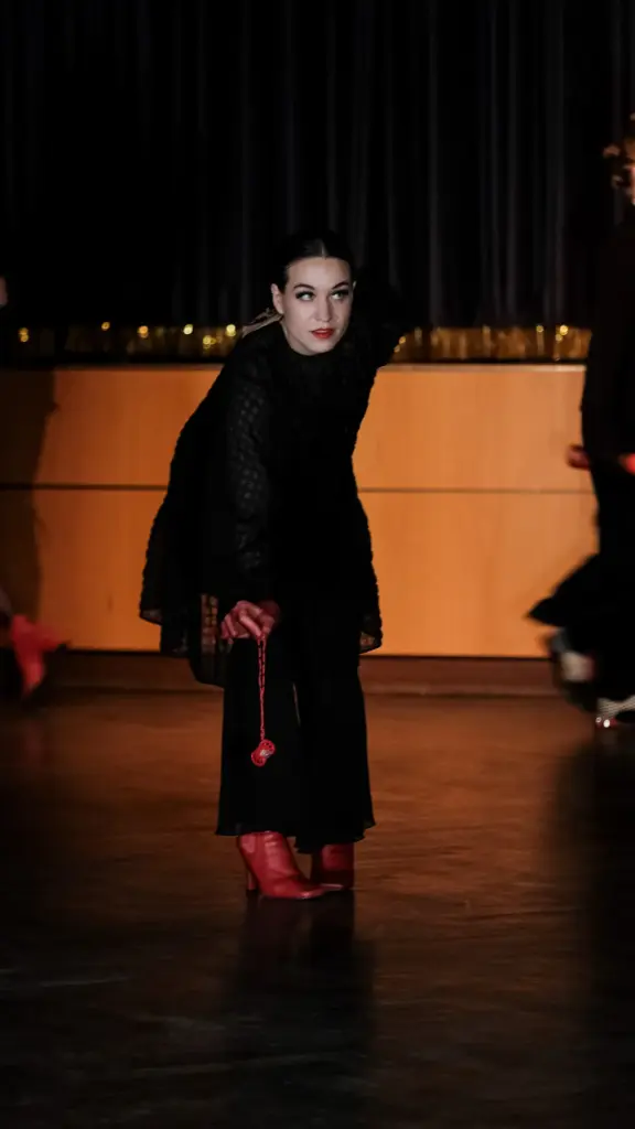 Schauspielerin in schwarzem Kostüm und roten Handschuhen allein auf der Bühne